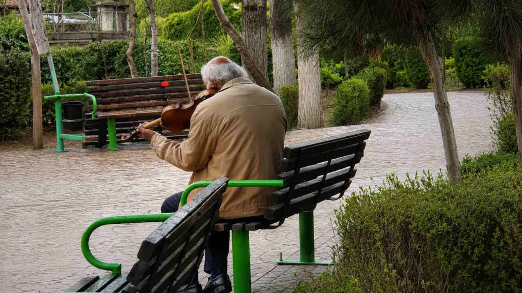 پیرمردی نشسته روی نیمکت در حال ویلون زدن- آزاده عباسی